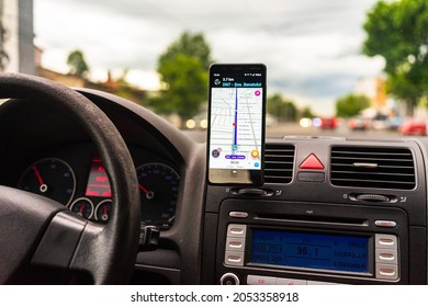 Driving and using waze maps application on smartphone on car dashboard, Driver using maps app for showing the right route through the traffic of city. Bucharest, Romania, 2020.