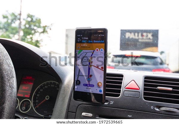 Driving and using waze maps application on\
smartphone on car dashboard, Driver using Waze maps app in\
Bucharest, Romania,\
2021