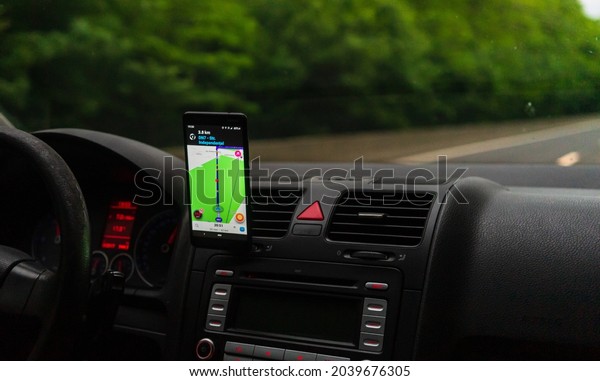 Driving and\
using waze maps application on smartphone on car dashboard, Driver\
using maps app for showing the right route through the traffic of\
city. Bucharest, Romania,\
2020.