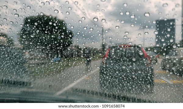 Drizzle on the windshield, Inside car when\
rainning, Road view through car window with rain drops. View\
through car window blurry with heavy\
rain.