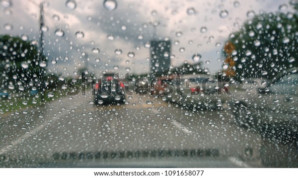 Drizzle on the windshield, Inside car when\
rainning, Road view through car window with rain drops. View\
through car window blurry with heavy\
rain.
