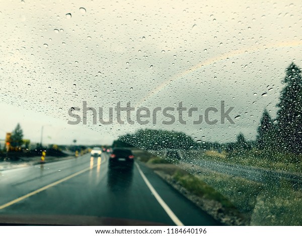 Drizzle on the windshield while driving in rain.
Wet road and rainbow in the
sky
