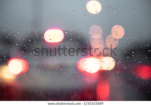 Drizzle rain\
drop on glass with street and cars lights at night blur bokeh\
abstract background. Raining season\
concept