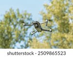 Dron with camera, The drone flies against the background of trees and sky, an unmanned flying object, The drone hovers in the air and records