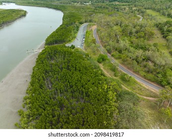 Drone Aerial Up A Creek At Low Tide Showing Boat Ramp And Jetty With Car Park And A Highway Through The Bush. Conway Beach, Queensland, Australia