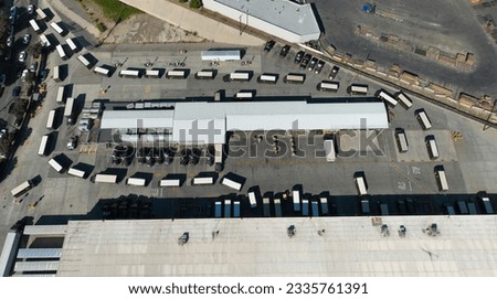 Drone aerial of delivery trucks leaving warehouse hub. Trucks and vans in rows. UPS (United Parcel Service) delivery van truck hub.