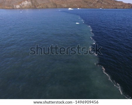 Drone aerial image of the sharp front dividing clear ocean waters from a turbid freshwater river plume fed by the melting of the Greenland Ice Sheet 