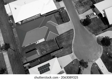 Drone Aerial Of Suburban Homes With Cars Parked In Driveways, Gardens And Street