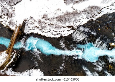 Drone aerial view of beautiful Bruarfoss waterfall with turquoise water and snow in winter, South Iceland