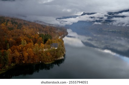 Drone Aerial view of bohinj lake reflecting cloudy sky during colorful autumn with fog covering forest and mountain - Powered by Shutterstock