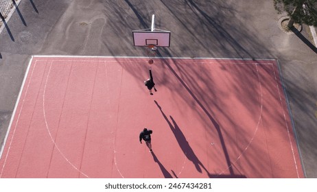 DRONE AERIAL VIEW - Brothers playing basketball One On One. Basketball players play a 1 on 1 game on an outdoor court. Sport and basketball concept. - Powered by Shutterstock