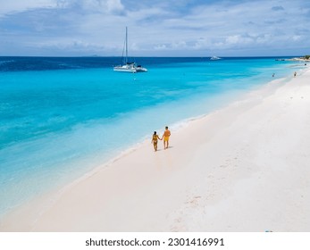 Drone aerial view of a couple of men and women on a white tropical beach during a boat trip to Small Curacao Island with a white beach and turqouse colored ocean