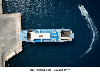 Drone Aerial view of a ferry docking at a pier as a jet ski circles nearby. Kefalonia Greece