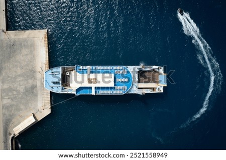 Drone Aerial view of a ferry docking at a pier as a jet ski circles nearby. Kefalonia Greece