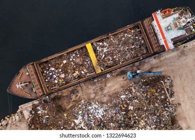 Drone aerial view loading in ship holds scrap metal for transportation. Collection of metal for secondary raw materials. Metallic trash for recycling. Black scrap, color scrap. Scrap import and export