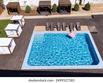 Drone aerial view of nflatable flamingo in pool. Pool party, summer holidays, beach vacation. Fantasy swim ring for summer pool trip drone top view from above