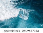 Drone aerial view of people surfing on the sea in Bali, Indonesia