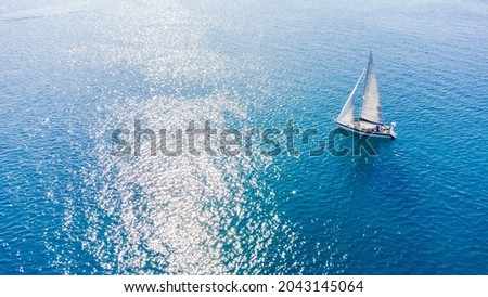 Drone aerial view of a sailing boat on a blue ocean sea waters.