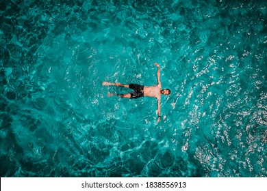 Drone areal view of young male in swimming pool floating - Powered by Shutterstock