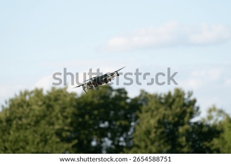 Drone with a camera, The drone flies against the background of trees and sky, unmanned aerial vehicle, The drone hovers in the air and records