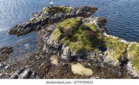 A drone captures a high-angle view of a rugged rocky island and its lighthouse.