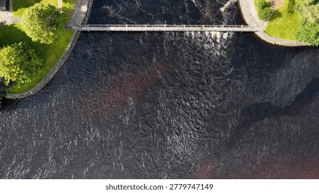 Drone captures a top-down perspective of a hydroelectric dam and dark flowing river water.