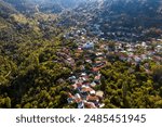 Drone capturing a picturesque village of Pedoulas nestled in a valley and surrounded by a lush green forest. Nicosia District, Cyprus