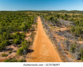 Drone Coming Into Land On A Red Dirt Road Amongst The Australian Scrub With A Vehicle Waiting.