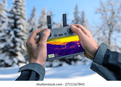 Drone controller with thermal imaging overlay used for search and rescue operations, highlighting heat signatures across forest terrain for emergency detection and safety missions