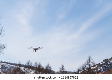 The Drone Flies Against The Sky. The Quadcopter Is Launched Above The House And Takes Video And Photographs From Above. Drone Outside The City