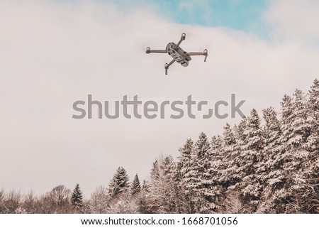The drone flies in the winter above the forest and shoots landscape videos.