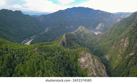 Drone flight above rocky mountain peaks covered with luxuriant and wild beech forests. The valley winds through sharp ravines and gorges. Olt river flows in the background. Carpathia, Romania. - Powered by Shutterstock