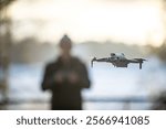 Drone in flight with pilot in background.