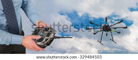 Drone flight remote controller in man's hands close up view and multicopter in flight
