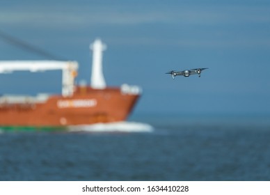 Drone Is Flying Above Sea. The Drone Will Fly To A Cargo Ship To Make Pictures. 