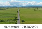 DRONE: Flying behind an autonomous car driving down the straight road leading through the lush green countryside in Austria. Futuristic self driving car navigates the rural motorway on a sunny day.