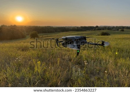 Drone flying in field at sunset. Inspection of a farmer's field with a drone. Drone flying in air over an agricultural field. Copter for photography and video