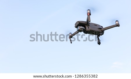 Drone flying over landscape. UAV drone copter flying with digital camera. Drone flying overhead in cloudy blue sky. Quad copter is flying over the  field.