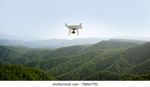 drone flying over mountains. white drone hovering in a bright blue sky. New technology in the aero photo shooting.