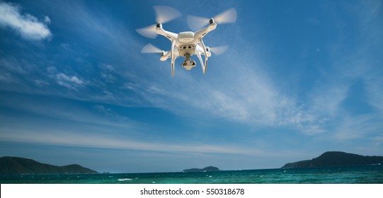 drone flying over sea. white drone hovering in a bright blue sky. New technology in the aero photo shooting.