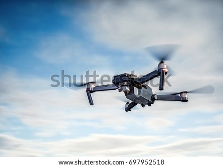 Drone flying overhead in cloudy blue sky