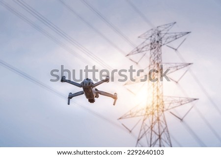 A drone is flying surveying equipment of high voltage pylons to inspect aerial view equipment on high voltage pylons. The concept of using technology instead of human labor