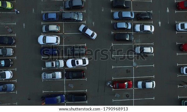 Drone footage cars\
parking at congested parking lots. Copter filming people walking\
around mall parking space. Drone flying above large parking place\
near supermarket.