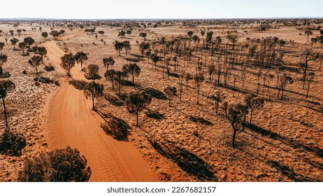 Drone footage of a gravel road in the Australian red centre. Orange road with trees on the side. Drone view of outback australia in Rainbow valley.  - Powered by Shutterstock