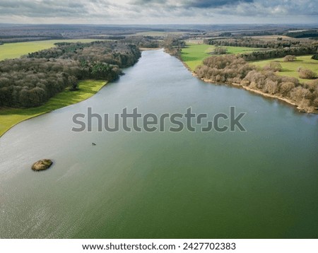 Drone high level view of a picturesque English lake and small island. A small fresh water fishing boat can be seen near the Island.