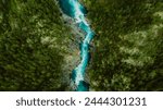 Drone high-angle photo of the turquoise-colored mountain river flowing in the pine woodland with a view of the mountain peaks in the background in Innlandet County, Norway