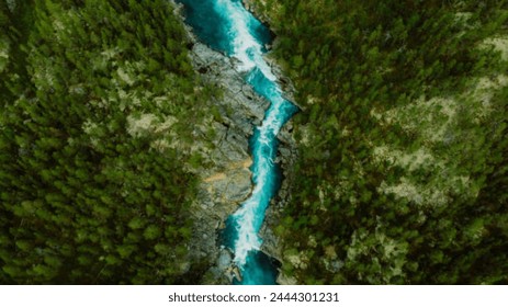 Drone high-angle photo of the turquoise-colored mountain river flowing in the pine woodland with a view of the mountain peaks in the background in Innlandet County, Norway - Powered by Shutterstock