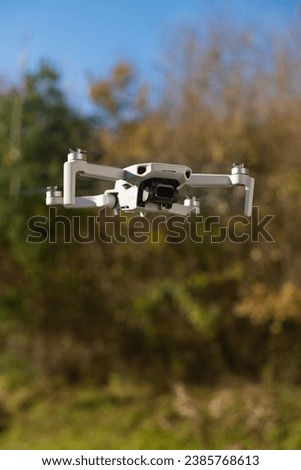 A Drone hovering in front of autumn Trees. Elevate your project with a compelling shot of this drone.