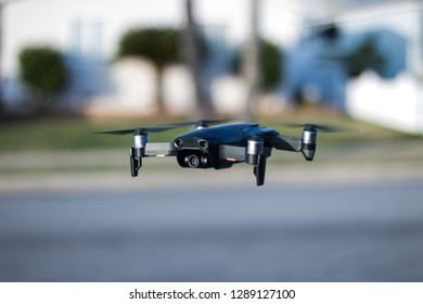 A Drone Hovering Over A Neighborhood Street.  Milky Bokeh In The Background. High Quality Camera On The Aircraft.