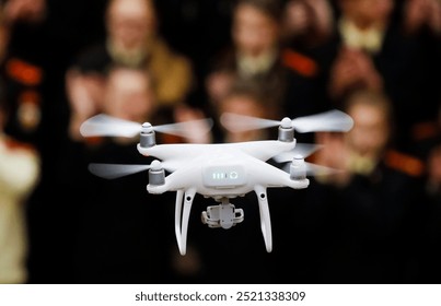 A drone hovers in front of an engaged audience inside a large indoor venue, showcasing advanced technology and capturing their attention during a demonstration event. - Powered by Shutterstock